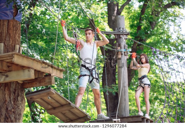 couple spend their leisure time in a\
ropes course. man and woman engaged in\
rock-climbing