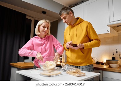 A couple spending quality time while preparing food together in a modern, comfortable kitchen setting.