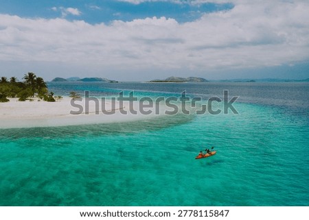 Couple spending time on a beutiful remote tropical island in the philippines. Concept about vacation and lifestyle.  kayaking and doing activities