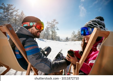 Couple Spending Time Together And Drink After Skiing In Cafe At Ski Resort In Mountains. Back View