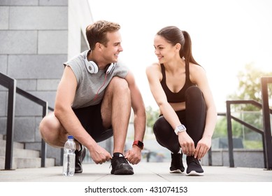 Couple squatting and tying their shoelaces - Powered by Shutterstock