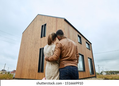 Couple stand and look at big new house