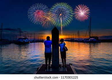 Couple stand on yacht boat pier look out to see and take photo colorful firework on the sky at night time