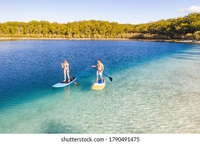 Couple Stand Up Paddle Boarding  On Lake Mckenzie, Fraser Island, Queensland, Australia