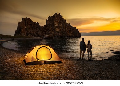 Couple stand at tent and Baikal lake shore and looking at the sunset - Powered by Shutterstock