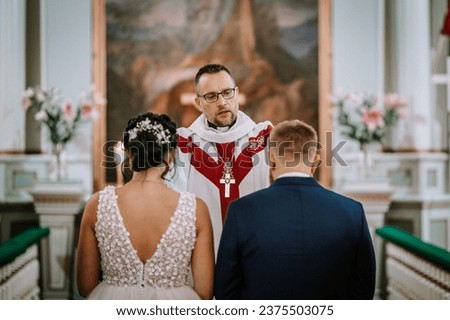 Couple standing before the priest for wedding ceremony in church. Bride and groom standing in the presence of priest during their wedding ceremony
