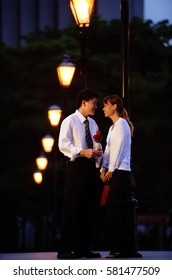 Couple Standing Face To Face, Man Holding Single Rose Stalk