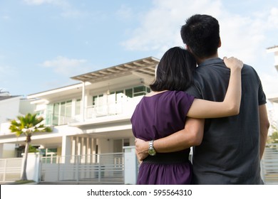 Couple standing in front of dream house in modern residential houses
