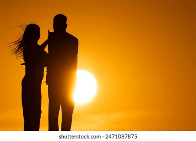 A couple standing in front of a sun with the woman touching the man's arm - Powered by Shutterstock