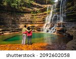 couple standing near waterfall flowing streams falling from mountain at morning from flat angle image is taken at wei sawdong falls cherrapunji sohra district meghalaya india.