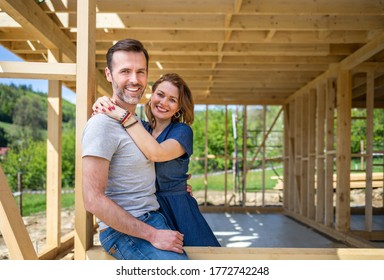 Couple standing on future window in construction site of their new house, dreams come true