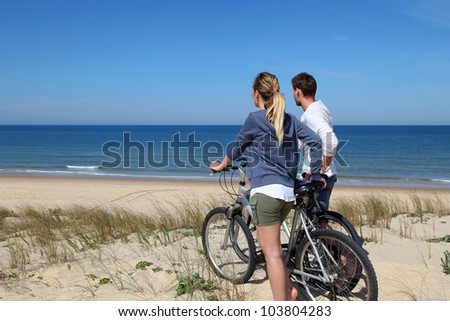 Couple standing on a sand dune with bicycles