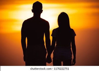 The couple standing on the sunset background