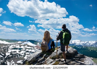 Couple standing on top of the mountain looking at beautiful view. People enjoying early summer landscape with green meadows and snow covered mountains.   Rocky Mountains National Park, Colorado, USA. - Powered by Shutterstock