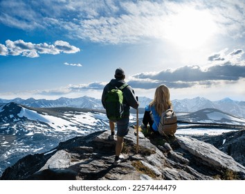 Couple standing on top of the mountain looking at beautiful view. People enjoying early summer landscape with green meadows and snow covered mountains.  Rocky Mountains National Park, Colorado, USA. - Powered by Shutterstock