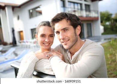 Couple Standing Outside In Front Of New Home
