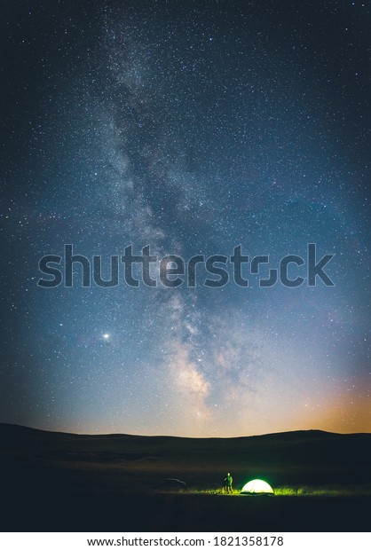 Couple stands by the
tent with car in the background and looks to the stary sky.Vertical
background image.