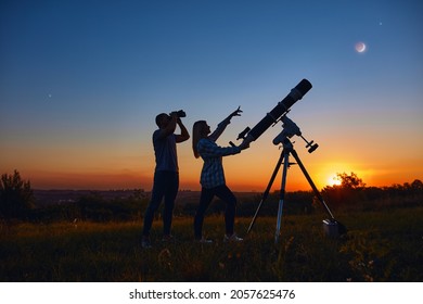 Couple Stargazing Together With A Astronomical Telescope.