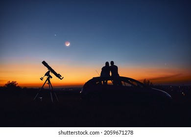 Couple Stargazing Together With A Astronomical Telescope.