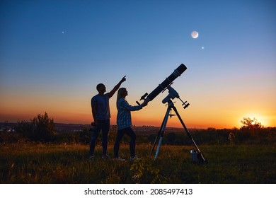 Couple Stargazing Together With A Astronomical Telescope.