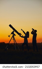 Couple Stargazing Together With A Astronomical Telescope.