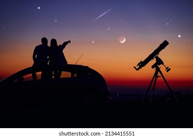 Couple Stargazing Together With A Astronomical Telescope.