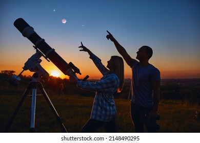 Couple Stargazing Together With A Astronomical Telescope.