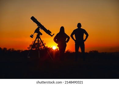 Couple Stargazing Together With A Astronomical Telescope.