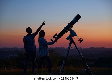 Couple Stargazing Together With A Astronomical Telescope.