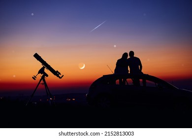 Couple Stargazing Together With A Astronomical Telescope.