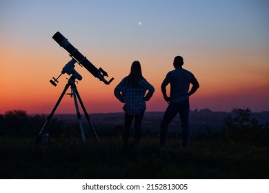 Couple Stargazing Together With A Astronomical Telescope.