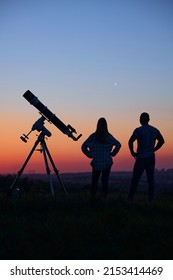 Couple Stargazing Together With A Astronomical Telescope.