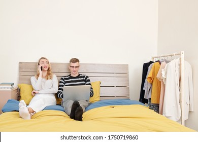 Couple Staying In Bed All Day, Man Working On Laptop And Woman Making Phones Call To Clients