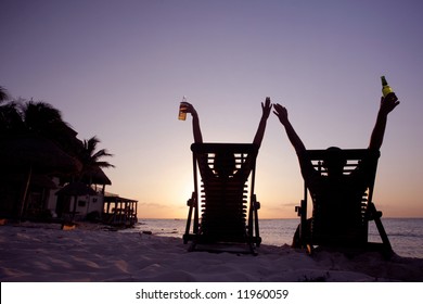 Couple stretching in deckchairs at sunset