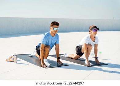 Couple Stretching on Yoga Mats During a Sunny Morning Workout Session on a Rooftop Terrace - Powered by Shutterstock