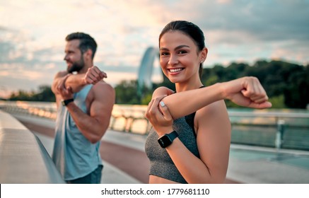 Couple stretching outdoors before morning run. Handsome bearded man and attractive sporty woman running on the street. - Shutterstock ID 1779681110