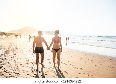 Couple strolled along the shore of the beach with mask. Couple holding hands on the beach with mask. Couple on the beach during pandemic.