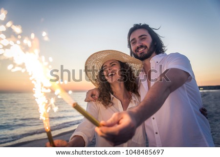Couple strolling at the beach and smiling - Young adults enjoying summer holidays on a tropical island
