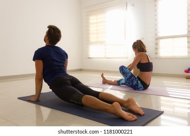 Couple Of Students Practice Yoga In Bright Studio. Young Man And Woman In Asthanga Mysore Style Class. Sitting Postures On Mat. Effort, Flexibility, Demanding, Healthy Lifestyle, Challenge Concepts