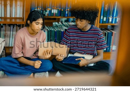 Couple study session on library floor with students reading books showing cooperative learning academic preparation calm atmosphere.