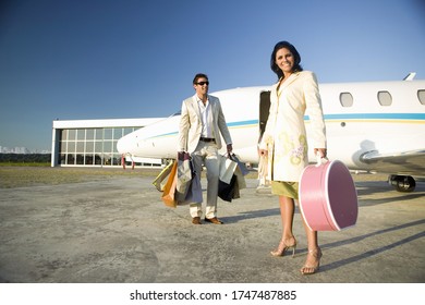 Couple with suitcases and shopping bags next to airplane - Powered by Shutterstock