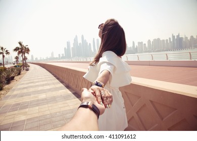 Couple summer vacation travel. Woman walking on romantic honeymoon promenade holidays holding hand of husband following her, view from behind. (focus on woman) - Powered by Shutterstock