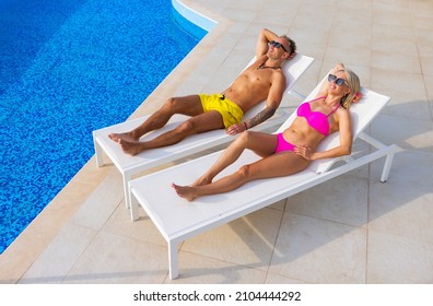 Couple Sunbathing By The Pool, View From Above