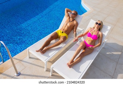 Couple Sunbathing By The Pool, View From Above