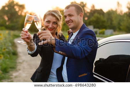 couple in the sunset, they are wearing smart casual clothes and drink champagne