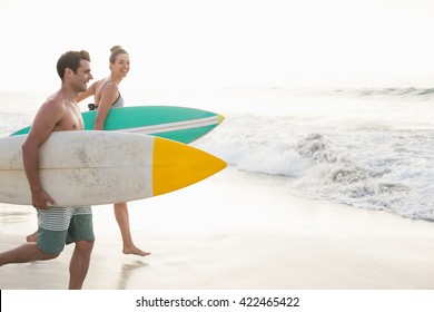 Couple with surfboard running on the beach on a sunny day - Powered by Shutterstock