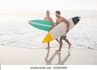 Couple with surfboard running on the beach on a sunny day - Powered by Shutterstock