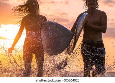 Couple Of Surfers Running With Boards And Lots Of Splashes