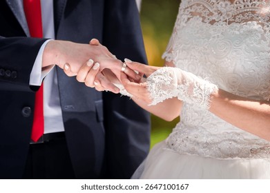 Couple swaps wedding rings. A couple exchanges rings in an outdoor wedding, capturing a moment of love and commitment on a beautiful day.