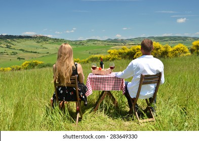 A couple at the table in the middle of a Tuscan field. Italy